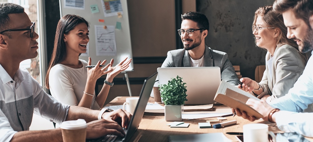 Happy business team working together while sitting at the desk in office